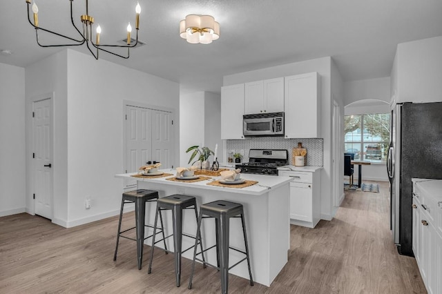 kitchen with white cabinetry, a center island, stainless steel appliances, light hardwood / wood-style flooring, and pendant lighting