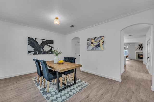 dining area featuring light wood-type flooring and crown molding