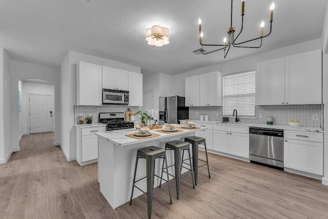 kitchen with white cabinets, sink, a breakfast bar area, a kitchen island, and stainless steel appliances