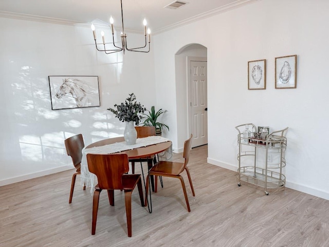 177 Oxford Dr, Kyle, TX 78640 - dining room featuring arched walkways, light wood-style floors, crown molding, a chandelier, and baseboards