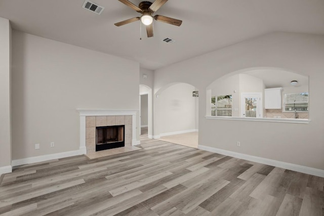 unfurnished living room with ceiling fan, light hardwood / wood-style flooring, and a tiled fireplace