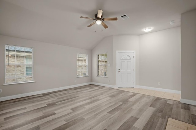 empty room featuring ceiling fan, plenty of natural light, light hardwood / wood-style floors, and lofted ceiling