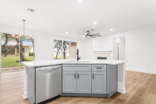 151 Dan Moody Trl, Georgetown, TX 78633 - kitchen with stainless steel dishwasher, gray cabinetry, light countertops, a kitchen island with sink, and a fireplace