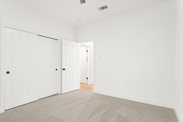 unfurnished bedroom with light carpet, a closet, and ceiling fan