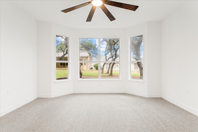 carpeted spare room featuring ceiling fan and plenty of natural light