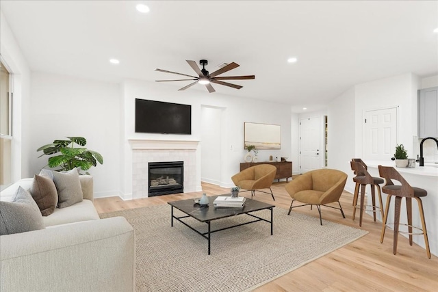 151 Dan Moody Trl, Georgetown, TX 78633 - living room featuring ceiling fan, light wood-style flooring, a tiled fireplace, and recessed lighting