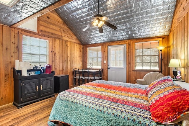 bedroom featuring vaulted ceiling, ceiling fan, wood-type flooring, and wood walls