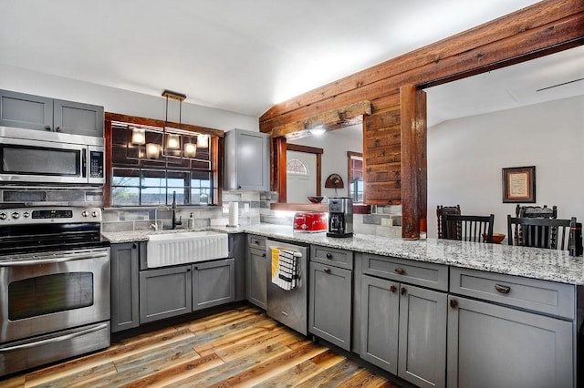 kitchen with gray cabinetry, hanging light fixtures, and stainless steel appliances