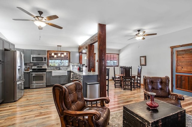 living room with ceiling fan, light wood-type flooring, and sink