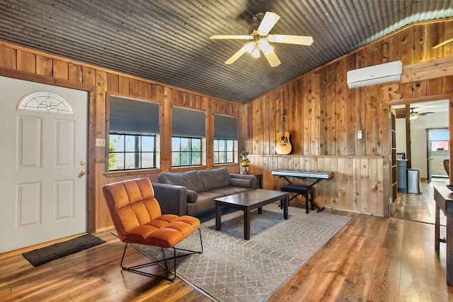 9475 N US Highway 377, Junction, TX 76849 - living area with a wall mounted AC, ceiling fan, wooden walls, lofted ceiling, and hardwood / wood-style floors