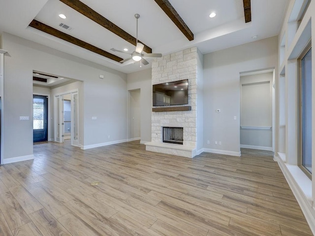 unfurnished living room with a raised ceiling, ceiling fan, a fireplace, and light hardwood / wood-style floors