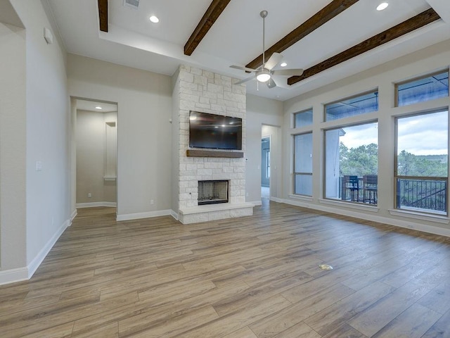 19516 Tranquility Falls Path, Lago Vista, TX 78645 - unfurnished living room with beamed ceiling, a ceiling fan, light wood-type flooring, a stone fireplace, and recessed lighting