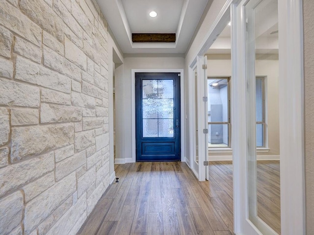 doorway to outside with a raised ceiling, hardwood / wood-style floors, and plenty of natural light