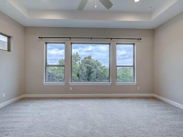 carpeted spare room featuring ceiling fan and a raised ceiling