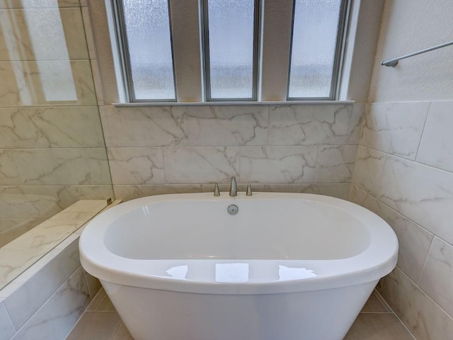 bathroom with tile patterned floors, a bathtub, and tile walls