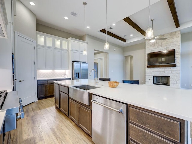 kitchen with beam ceiling, white cabinetry, light hardwood / wood-style floors, decorative light fixtures, and appliances with stainless steel finishes