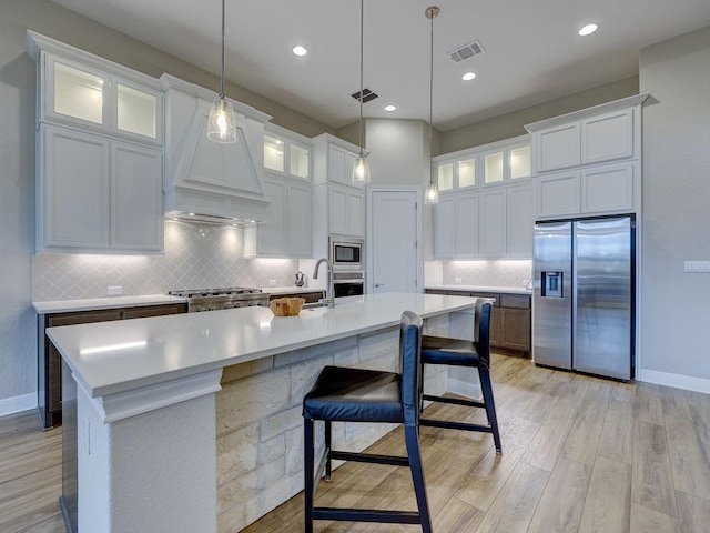 kitchen with a kitchen island with sink, white cabinets, hanging light fixtures, and appliances with stainless steel finishes