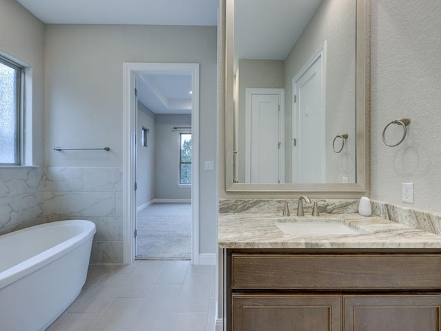 bathroom with a tub, plenty of natural light, vanity, and tile walls