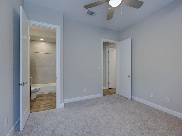 unfurnished bedroom with light carpet, connected bathroom, and ceiling fan