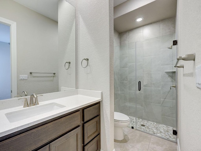 bathroom featuring tile patterned floors, a shower with door, vanity, and toilet