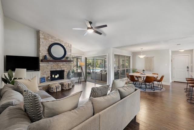 living room with ceiling fan, a fireplace, dark wood-type flooring, and lofted ceiling