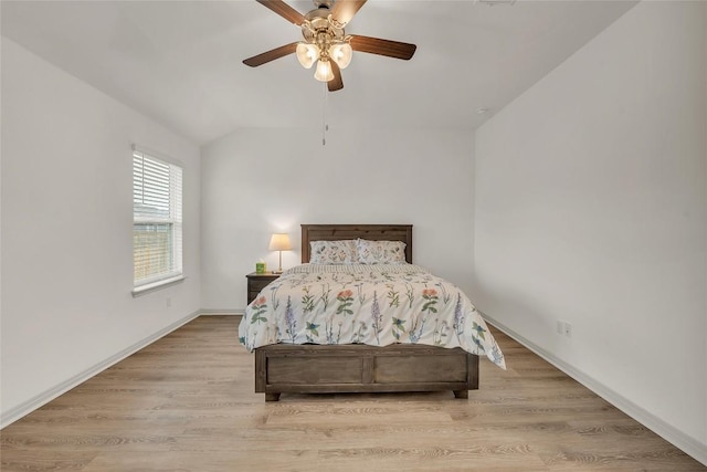 bedroom with ceiling fan, light hardwood / wood-style floors, and vaulted ceiling