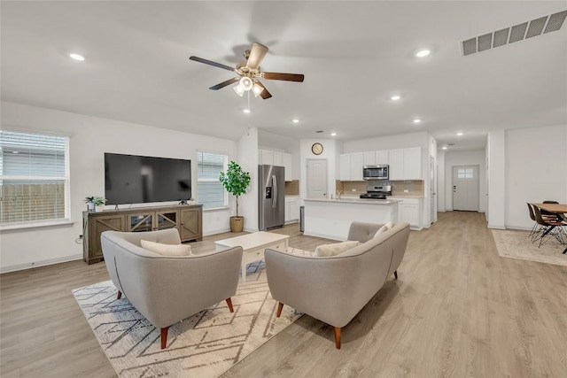 living room with ceiling fan and light hardwood / wood-style flooring