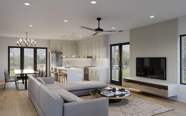 living room featuring ceiling fan with notable chandelier, light wood-type flooring, a healthy amount of sunlight, and sink