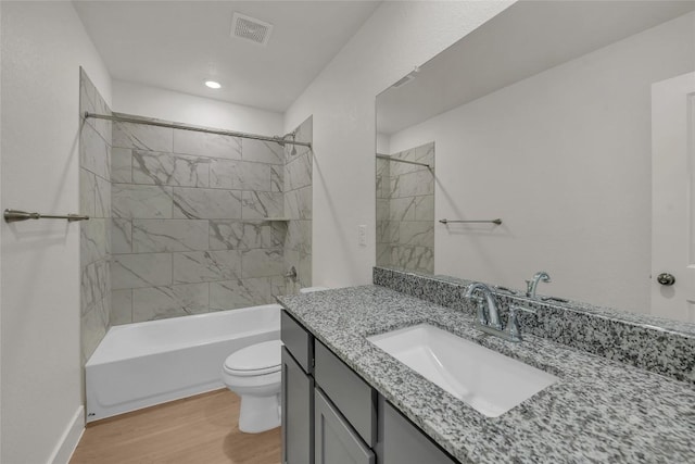 full bathroom with hardwood / wood-style floors, vanity, toilet, and tiled shower / bath