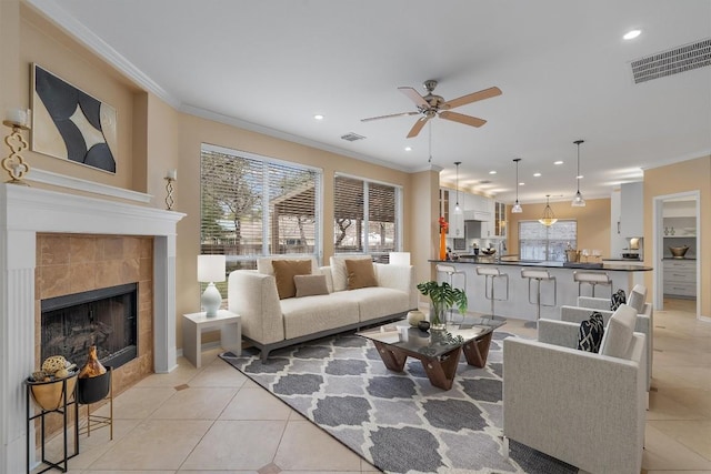 tiled living room with a tile fireplace, ceiling fan, and crown molding