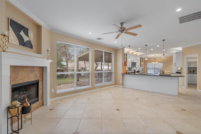 living room with a tiled fireplace, crown molding, light tile patterned floors, and ceiling fan