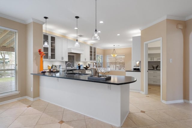 kitchen featuring kitchen peninsula, sink, light tile patterned floors, decorative light fixtures, and white cabinets