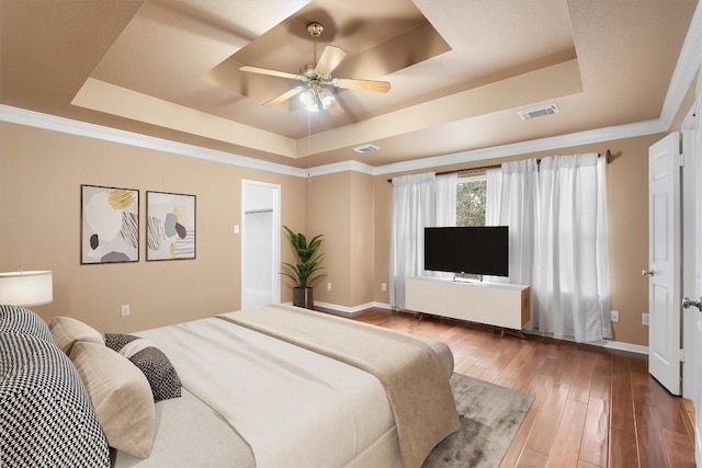 bedroom featuring a raised ceiling, ceiling fan, hardwood / wood-style floors, and ornamental molding