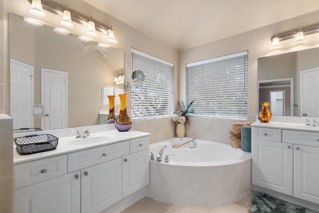 bathroom with tile patterned flooring, a washtub, lofted ceiling, and vanity