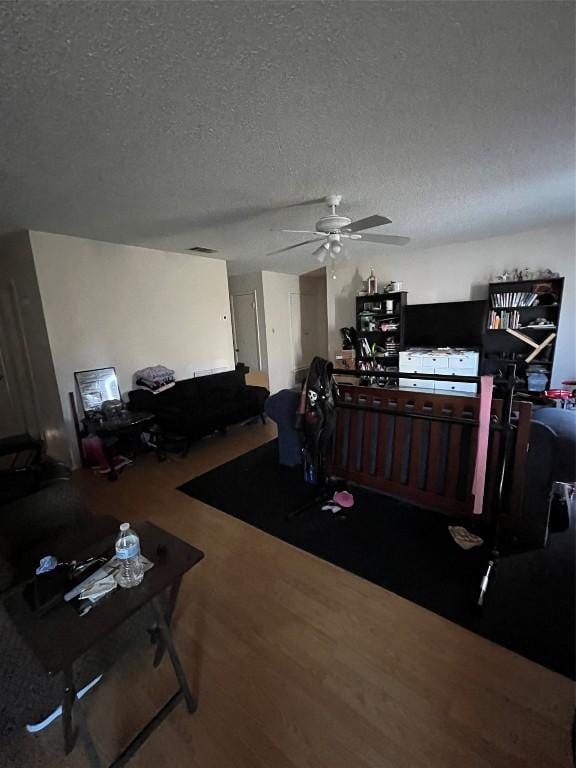 interior space with ceiling fan, wood-type flooring, and a textured ceiling