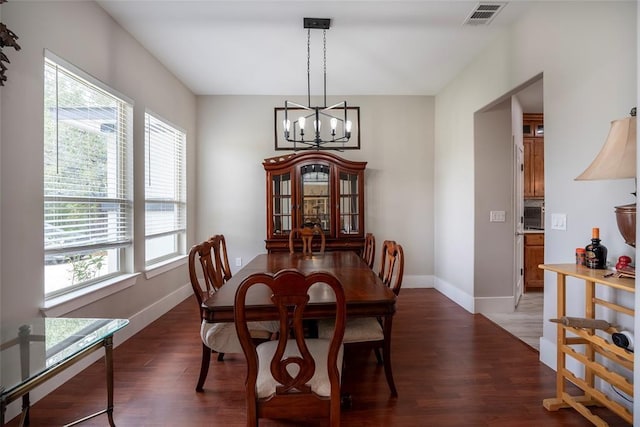 dining space with a notable chandelier, a healthy amount of sunlight, and dark hardwood / wood-style flooring