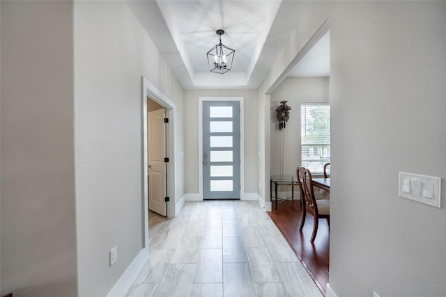 foyer with a tray ceiling and a chandelier