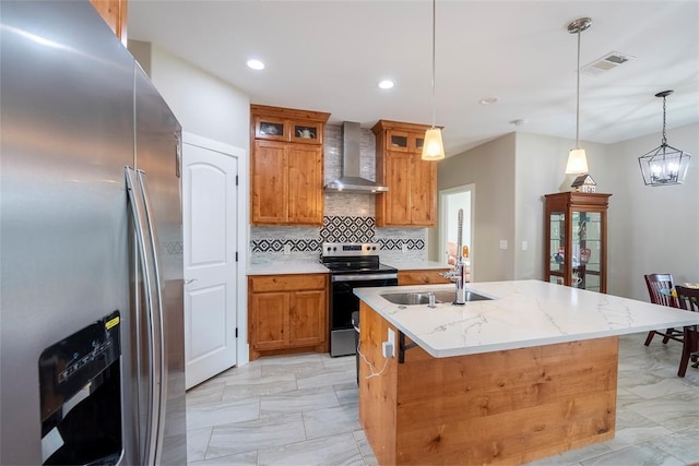 kitchen with sink, hanging light fixtures, wall chimney exhaust hood, an island with sink, and stainless steel appliances