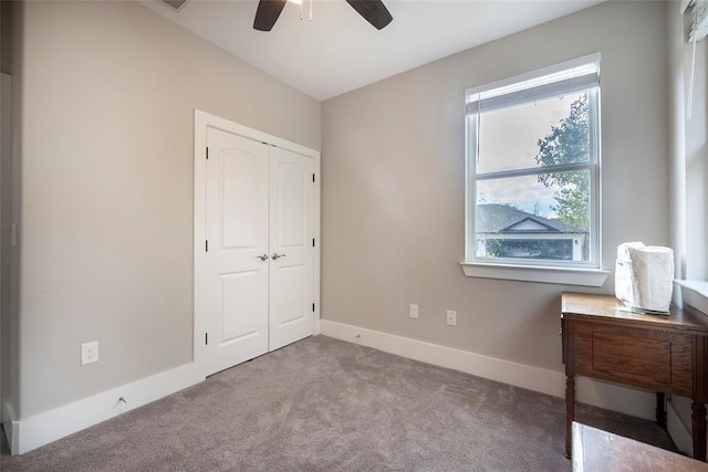 unfurnished bedroom featuring ceiling fan, light colored carpet, and a closet