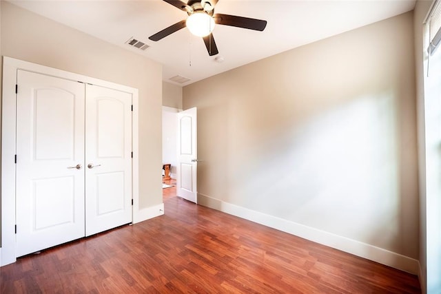 unfurnished bedroom featuring ceiling fan, dark wood-type flooring, and a closet