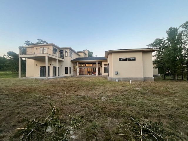 back of property with a yard, a balcony, and a patio