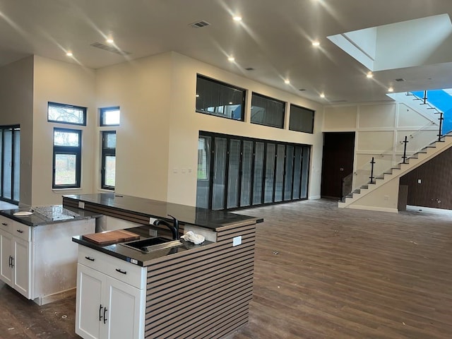 kitchen featuring white cabinets, a towering ceiling, a center island, and sink