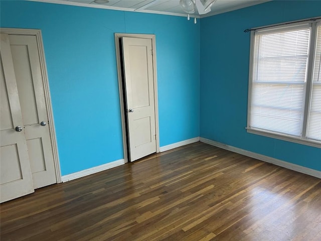 empty room with ceiling fan, dark hardwood / wood-style flooring, and ornamental molding