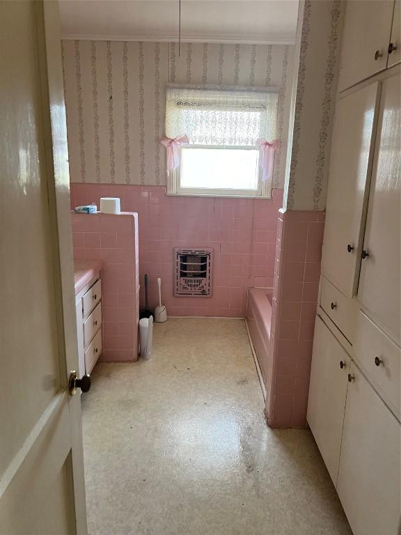 bathroom featuring vanity, heating unit, and tile walls