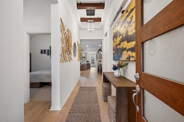 corridor with light hardwood / wood-style floors and beamed ceiling