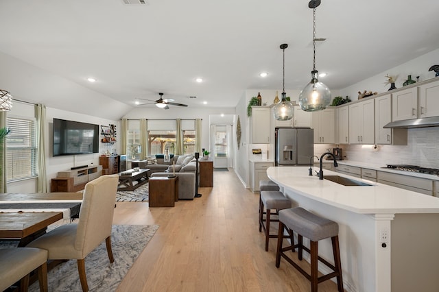 kitchen featuring sink, tasteful backsplash, decorative light fixtures, a center island with sink, and appliances with stainless steel finishes