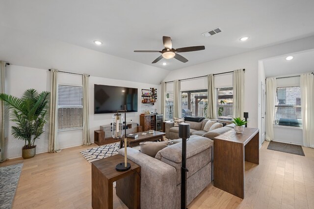 living room with light wood-type flooring, vaulted ceiling, ceiling fan, and plenty of natural light