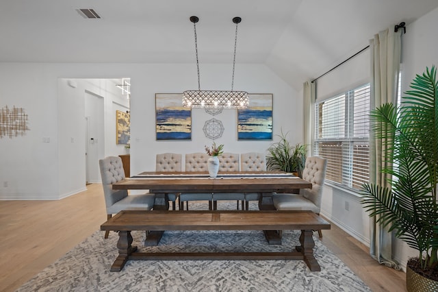 dining space featuring vaulted ceiling and light hardwood / wood-style floors