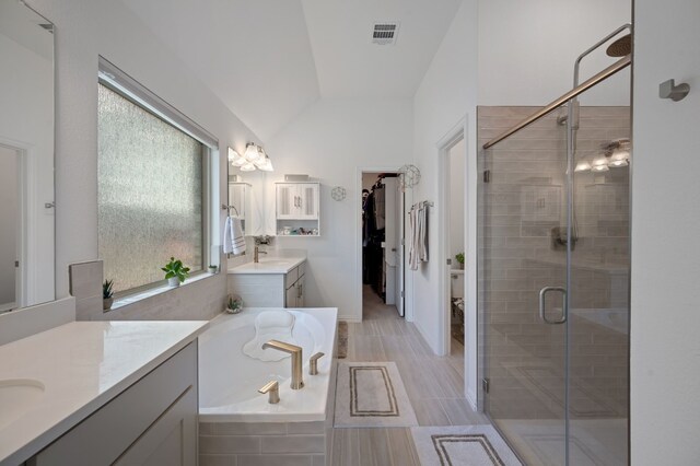 bathroom with independent shower and bath, vaulted ceiling, and vanity