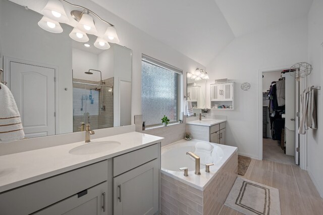 bathroom featuring an inviting chandelier, lofted ceiling, shower with separate bathtub, and vanity